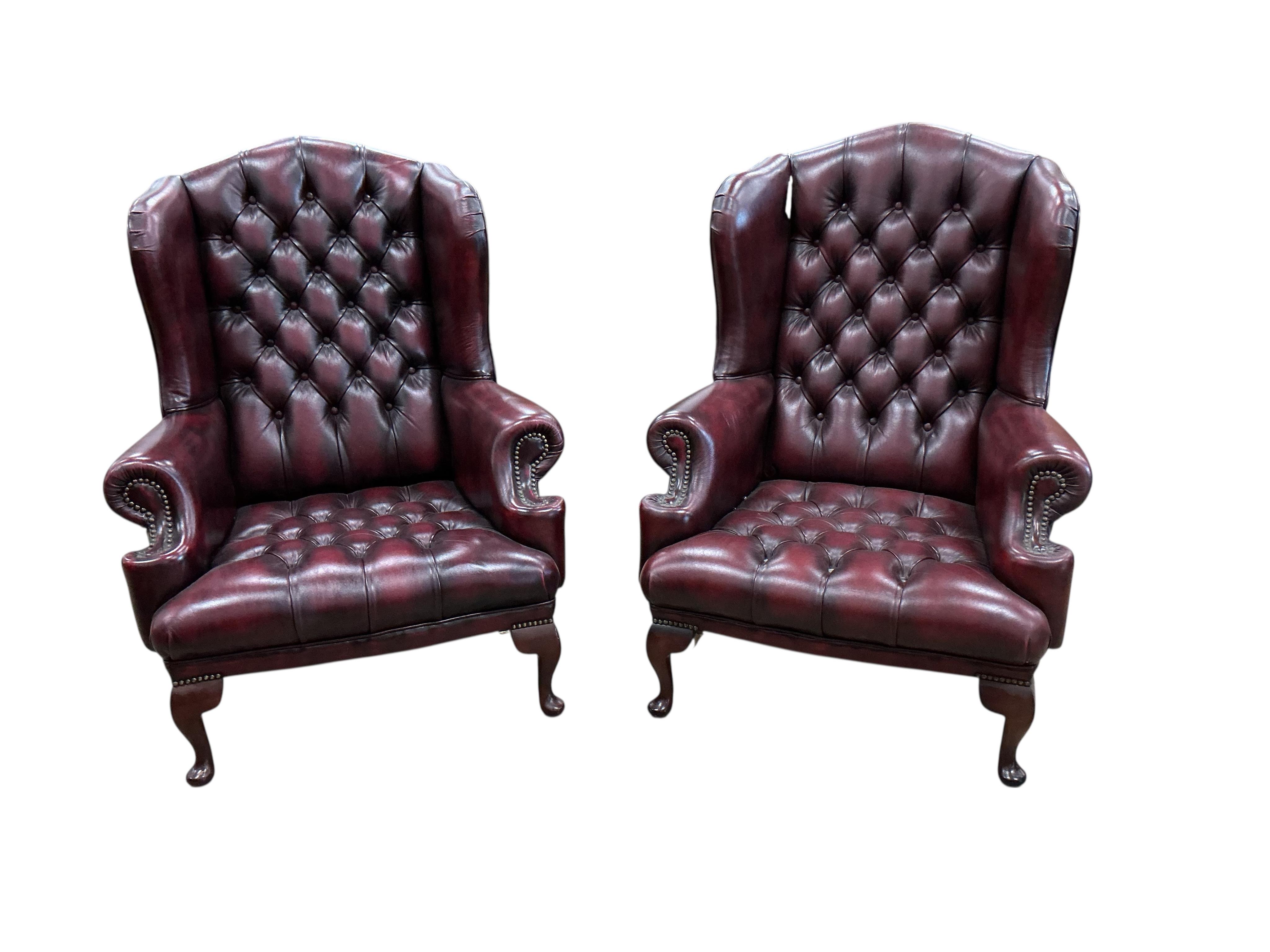A pair of reproduction buttoned burgundy leather wing armchairs, width 82cm, depth 70cm, height 104cm